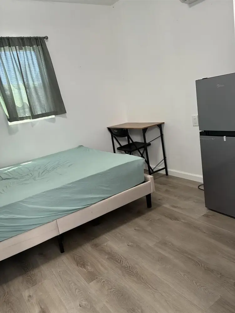 A bedroom with mini-split/fridge