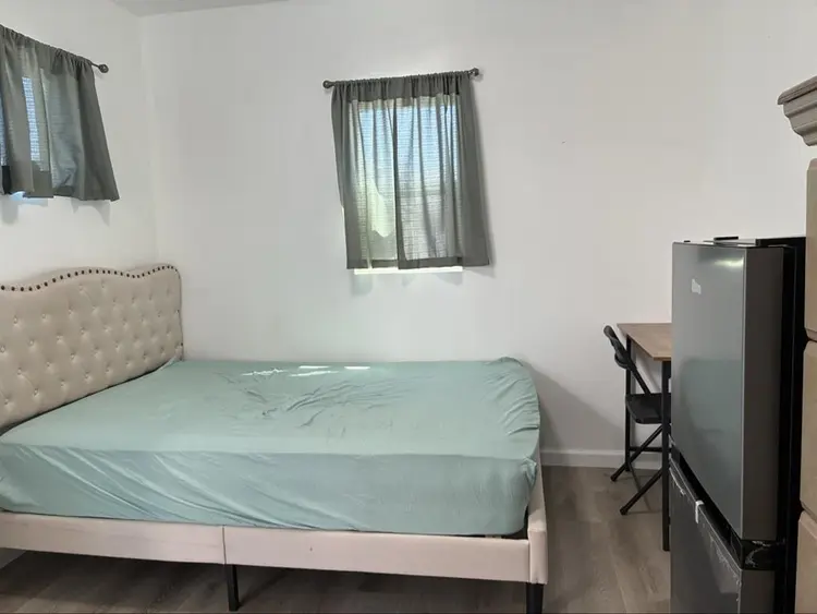 A bedroom with mini-split/fridge